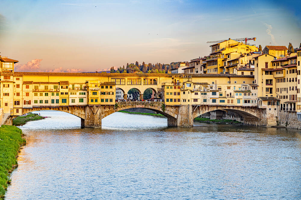 The sun sets over the Ponte Vecchio and the Arno in Florence