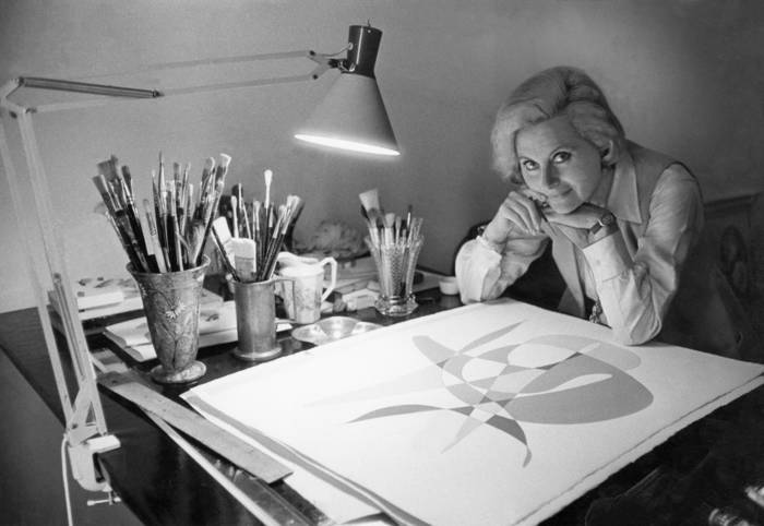 Michèle Morgan zittend aan haar tekentafel